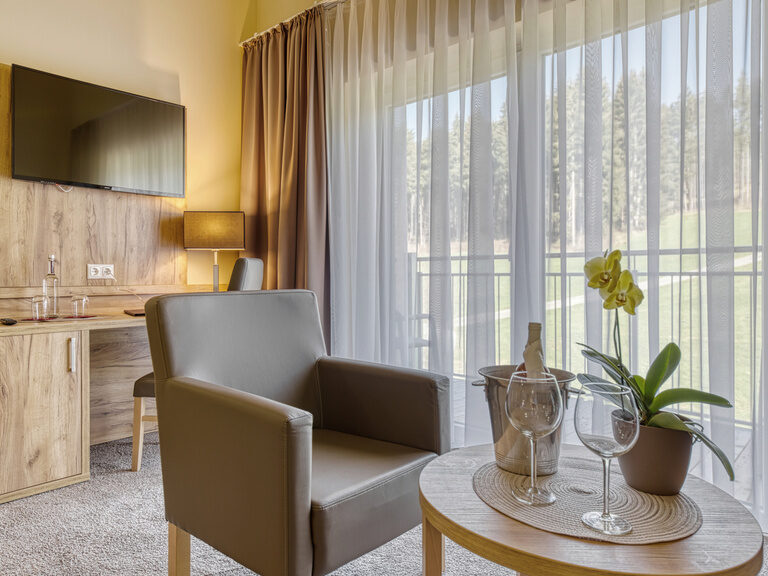 Moderne Einrichtung eines Hotelzimmers mit Tisch, Stuhl und Fernseher im Hotel Deine Auszeit im Bayerischen Wald